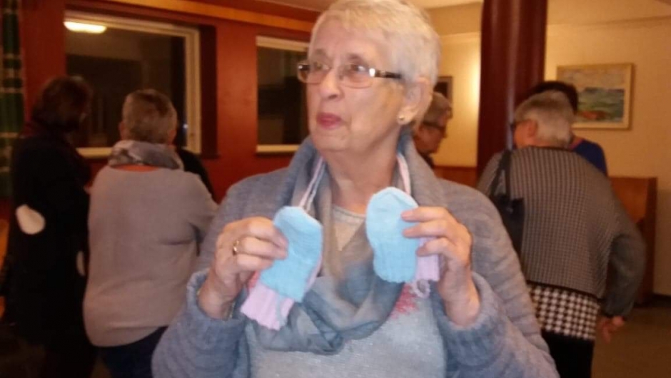 Åse med sine hjemmestrikkede babysokker som vi leverer på helsestasjonen