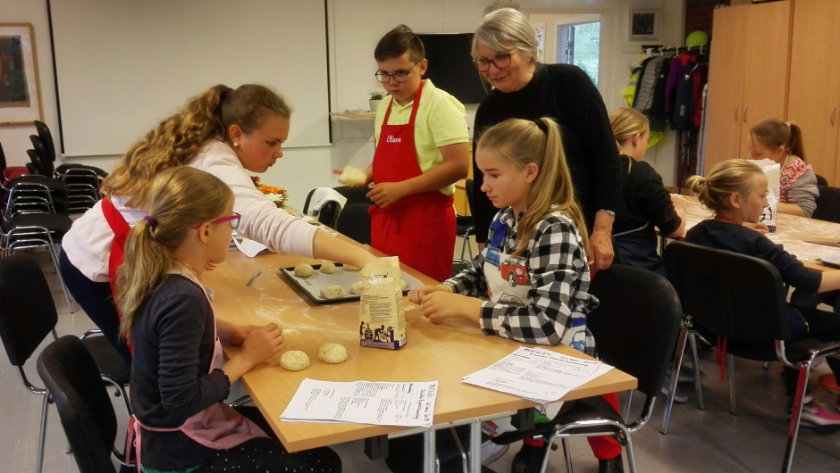 Bitten ser at Henriette, Tilla og de andre baker ut rundstykkene Bitten ser at Henriette, Tilla og de andre baker ut rundstykkene